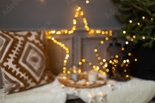 Blurred photo of tray with jar of milk and mug placed on bench next to garland star and pillow