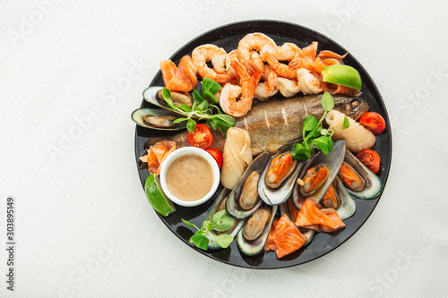 Obraz na płótnie Roasted Mixed Seafood Contain Mussels, prawns, salmon, Calamari Squids and Grilled Barracuda Fish Garlic with Spicy Chili Sauce. Isolated on White Background. Seafood and meat platter.Horizontal w salonie
