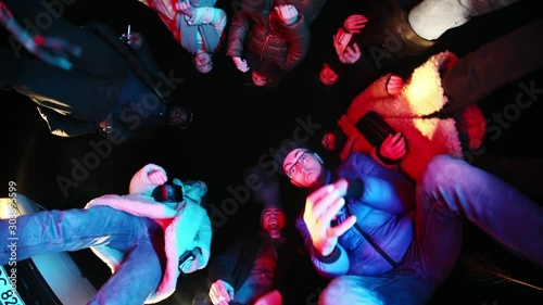 Bottom view of group of friends reading rap and gesticulating looking at camera. Fun youth party at night. photo