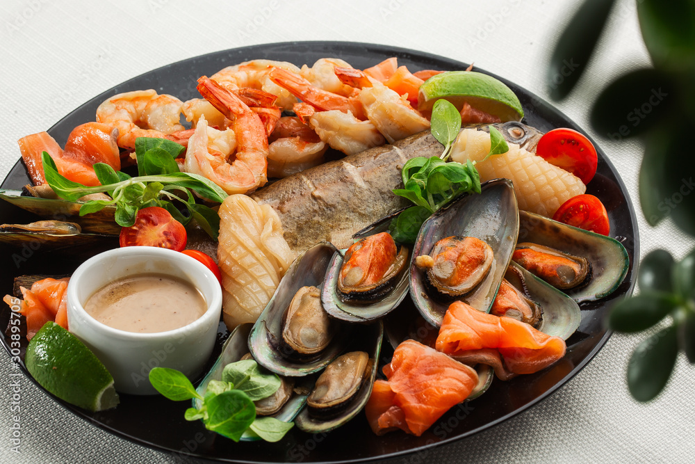 Roasted Mixed Seafood Contain Mussels, prawns, salmon, Calamari Squids and Grilled Barracuda Fish Garlic with Spicy Chili Sauce. Isolated on White Background. Seafood and meat platter.Horizontal
