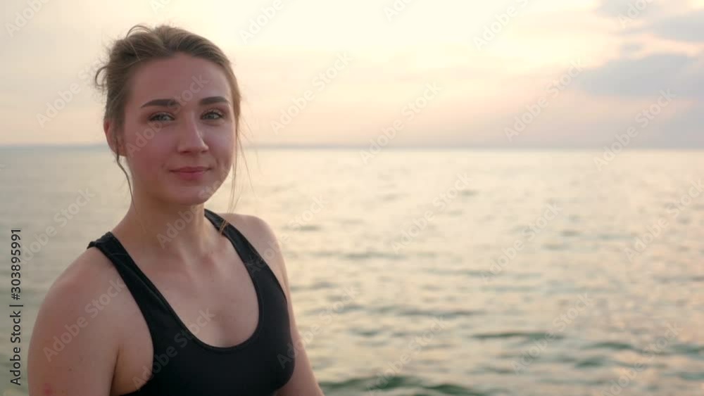 portrait of smiling woman after jogging near sea on sunrise portrait of smiling woman after jogging near sea on sunrise