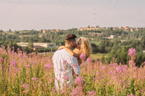 Young man hugging and kissing his girlfriend in the field