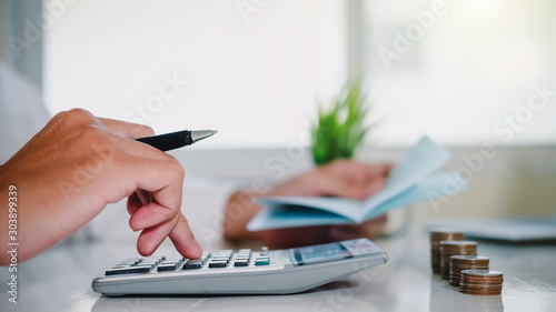 asian man working with calculator to calculate numbers. expenses calculator, payments costs with paper notes, payments table. Financial and Installment payment concept. Saving concept - Image photo