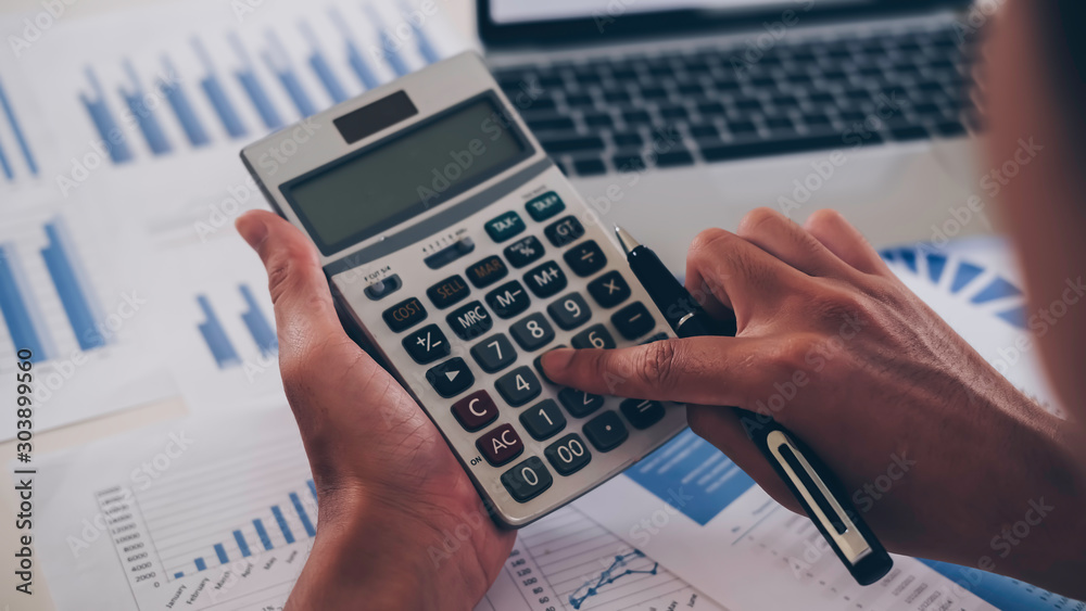 Αυτοκόλλητο asian businessman or accountant working pointing graph discussion and analysis data charts and graphs and using a calculator to calculate  numbers