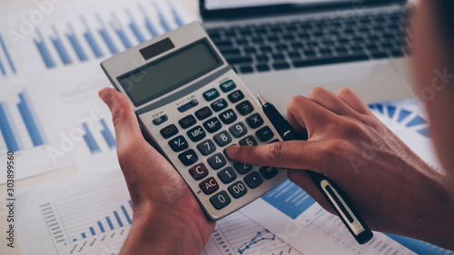 asian businessman or accountant working pointing graph discussion and analysis data charts and graphs and using a calculator to calculate  numbers.Business finances and accounting concept