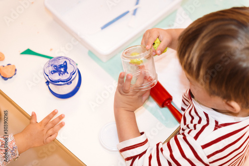 two kids playing with Montessori resources in a table with some tools and clay  photo