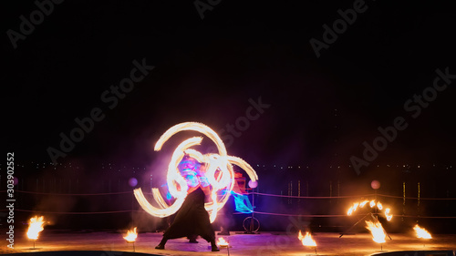 Artists juggling with burning poi s at fire performance.