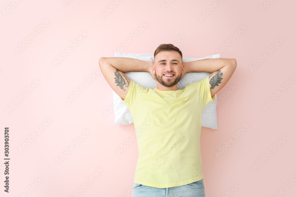 Young man with pillow on color background Young man with pillow on color background