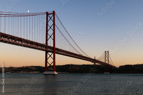 Fototapeta Naklejka Na Ścianę i Meble -  View of the 25 of April Bridge (Ponte 25 de Abril) over the Tagus River, in the city of Lisbon, Portugal; Concept for travel in Portugal