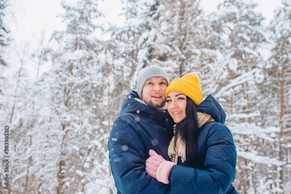 young couple in love walks in the winter forest. active winter holidays. A couple hugs and laughs on a background of a snowy forest. Closeup portrait of a guy and a girl in a snowy forest. young couple in love walks in the winter forest. active winter holidays. A couple hugs and laughs on a background of a snowy forest. Closeup portrait of a guy and a girl in a snowy forest.