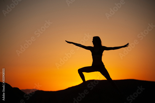 Yoga woman silhouette in the desert sunset.  © Elena Ray