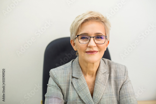 adult woman in a suit and glasses at a table indoors