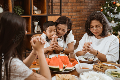 christian family praying before meals. portrait of people having lunch on christmas day