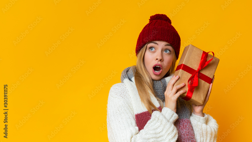 Surprised girl with new year gift looking at copy space Surprised girl with new year gift looking at copy space