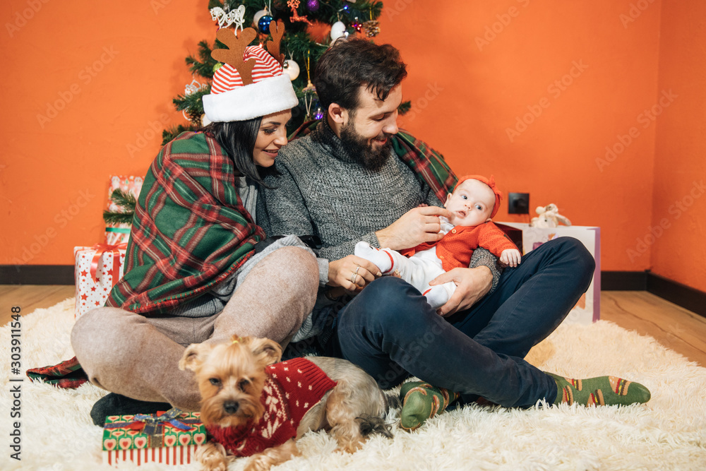 Φωτογραφία young family with a child near the Christmas tree, mom dad and their newborn dau
