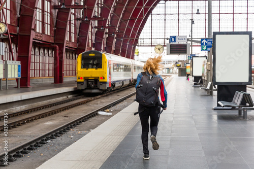 Female tourist with backpack running to the train