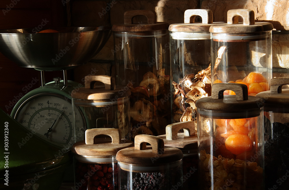 Dried fruits in glass jars with wooden lids in the rays of light Dried fruits in glass jars with wooden lids in the rays of light