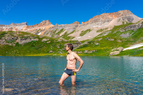 Young fit man standing in cold colorful water of Ice Lake on famous trail in Silverton, Colorado in San Juan Mountains in summer swimming © Kristina Blokhin