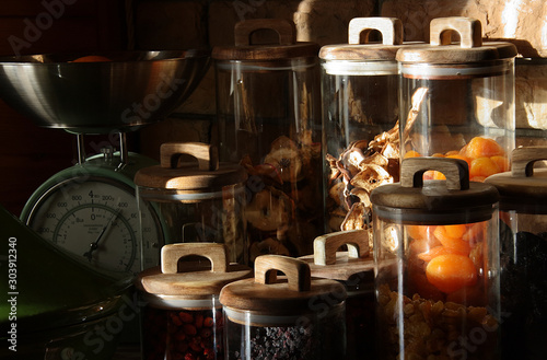 Fototapeta Naklejka Na Ścianę i Meble -  Dried fruits in glass jars with wooden lids in the rays of light