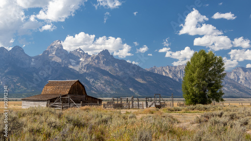 Deserted wooden barn on the prairy with mountains and a cloudy sky in the background