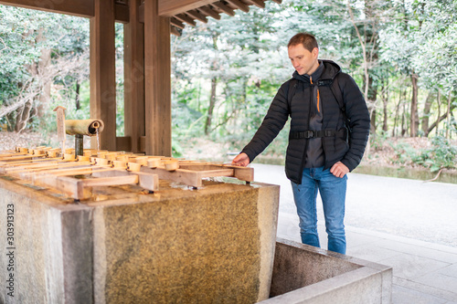 Photography Tokyo, Japan Meiji shrine architecture with young tourist man using purification