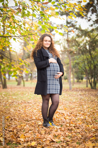 Happy pregnant young woman in autumn background