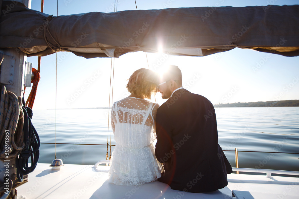 Beautiful wedding couple on yacht at wedding day outdoors in the sea. Beautiful elegant  bride in a white dress and stylish groom on the luxury yacht sailing down the sea. Together. Wedding day.