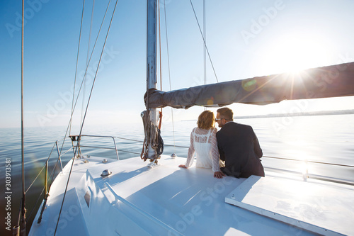 Beautiful wedding couple on yacht at wedding day outdoors in the sea. Beautiful elegant  bride in a white dress and stylish groom on the luxury yacht sailing down the sea. Together. Wedding day. © maxbelchenko