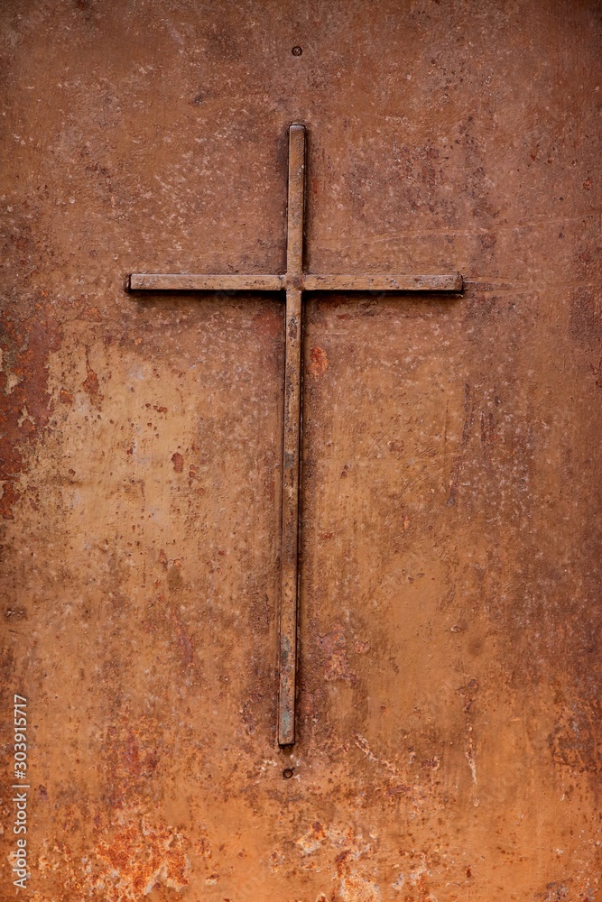 A steel Christian cross on a medieval door. Christianity concept image. 