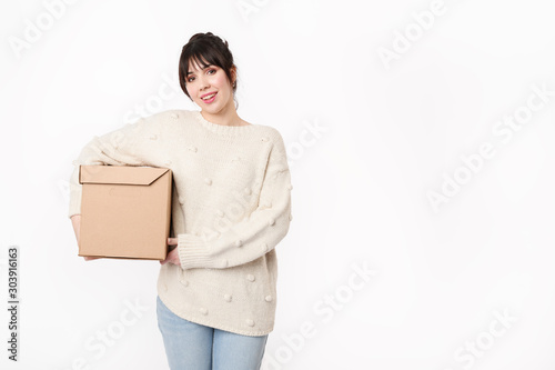 Pretty brunette woman holding  in armpit closed cardboard box with free copy space on grey background. Moving day concept. ..packing unnecessary things at home. online order delivery © Galina_lya