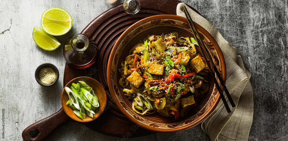 Ταπετσαρία banner of Asian vegan stir fry with tofu, rice noodles and vegetables, top view