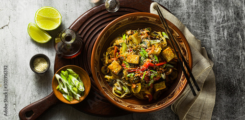 Photos banner of Asian vegan stir fry with tofu, rice noodles and vegetables, top view