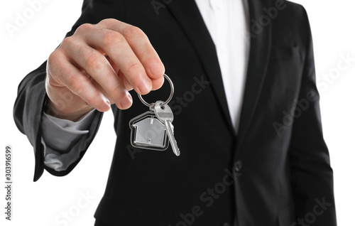 Real estate agent holding house key with trinket on white background, closeup