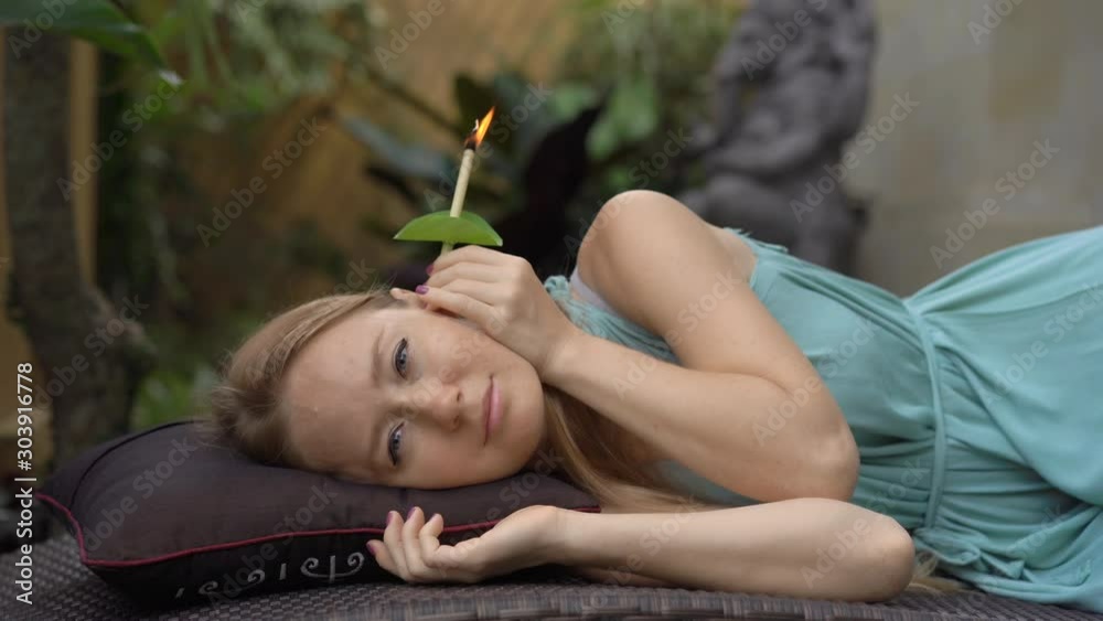 Ear candling being carried out on an attractive caucasian woman in a spa Ear candling being carried out on an attractive caucasian woman in a spa
