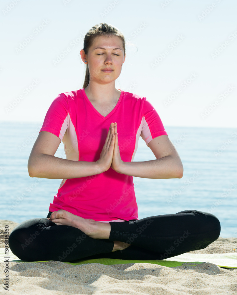Girl practicing yoga poses on beach