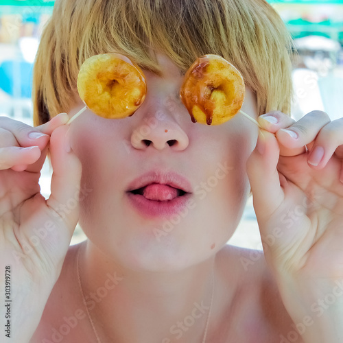Playful girl holding donuts on her eyes.