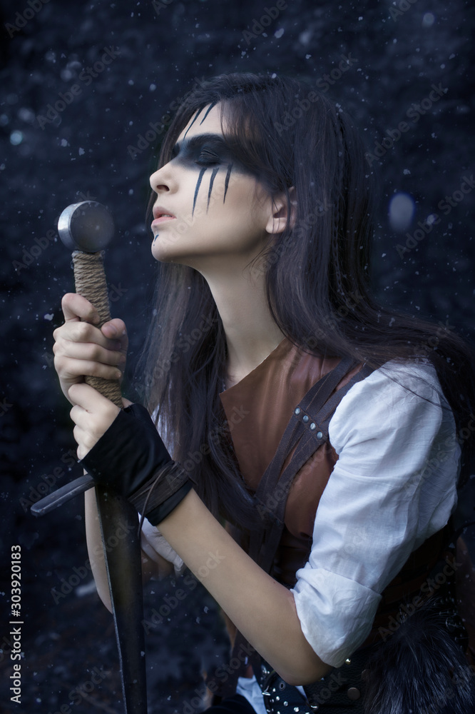 Φωτογραφία Art photo of a warrior girl with a sword in prayer among the falling snow
