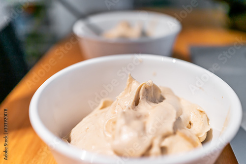 Soft serve vanilla ice cream bowls with bokeh background of table and laptop computer made with banana nice cream vegan dessert