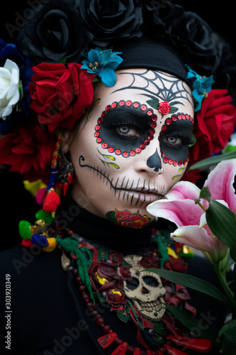 Fototapeta Naklejka Na Ścianę i Meble -  Girl in makeup on the day of the dead with pink lilies