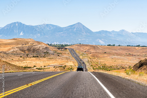 Road highway 92 in Delta, Colorado near Montrose towards Paonia with dry desert landscape view and rocky mountains with cars on street traffic photo