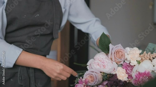 Female florist putting ribbon on fresh bouquet