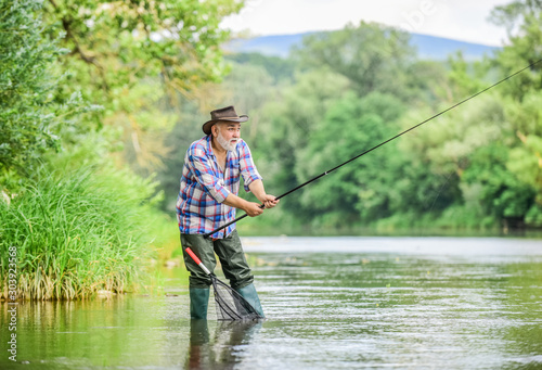 Fishers have long rods. retired bearded fisher. Trout bait. fisherman with fishing rod. mature man fly fishing. man catching fish. hobby sport activity. pothunter. summer weekend. Big game fishing