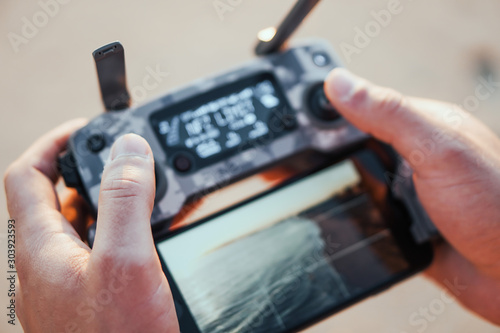 Young man are holding his drone controller in army skin.