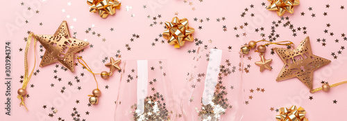 Christmas flat lay. Champagne glasses and gold decoration on pink background. Horizontal banner - Image