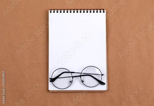 Stationary concept, Flat Lay top view Photo of glasses and notepad on a beige abstract background with copy space, minimal style.
