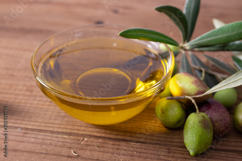 bowl of olive oil and olives with olive branches