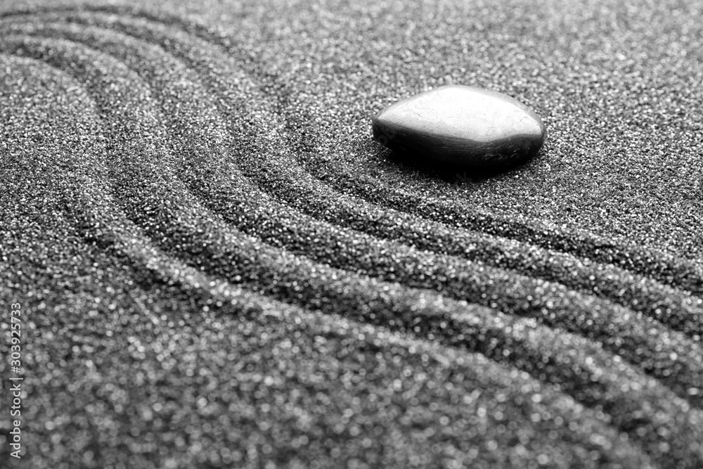 Obraz premium Zen garden stone on black sand with pattern, closeup