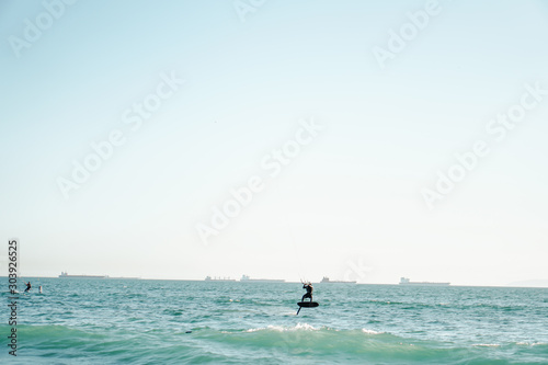 Professional kiter rides on the waves, jumps on the sea.