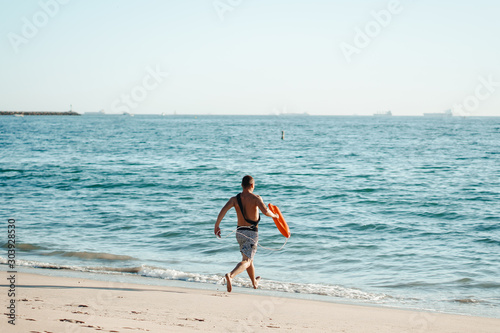 Male lifeguard running on the beach.