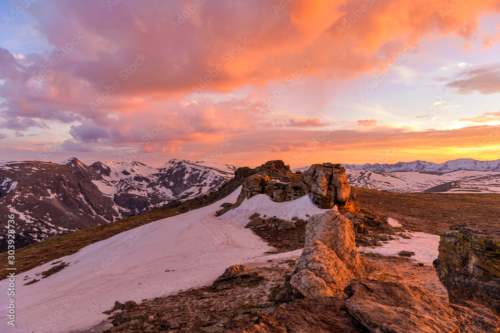 Sunset Mountain Top - Colorful Spring sunset clouds hanging over snow-capped high peaks of the Continental Divide at top of Rocky Mountain National Park, Colorado, USA. 